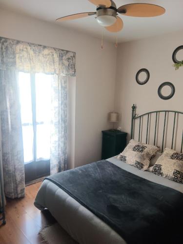 a bedroom with a bed with a ceiling fan and a window at Apartamento OGUM Cáceres in Cáceres