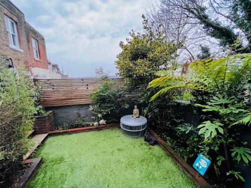 a small garden with a bench and grass at Stylish Brighton Haven, Sleeps 1 to 7, free parking in Brighton & Hove
