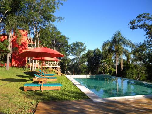 a pool with chairs and a red umbrella and a table at El Soberbio Lodge in El Soberbio