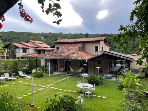 a house with a yard with a table and chairs at Pousada Monteflor Guaramiranga-CE in Guaramiranga