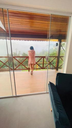 a woman walking on a balcony looking out of a mirror at A Casa do Júnior em Visconde de Mauá in Visconde De Maua