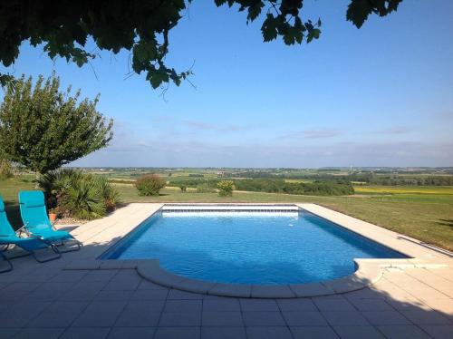 - une piscine avec deux chaises bleues à côté dans l'établissement Les Roses Tremieres, à Saint-Fort-sur-Gironde
