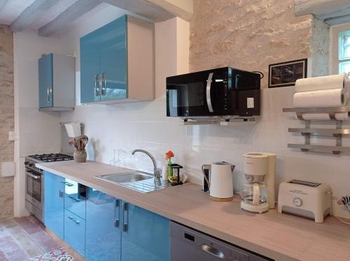 une cuisine avec des armoires bleues et un comptoir dans l'établissement La Romanella, à Asnières-sous-Bois