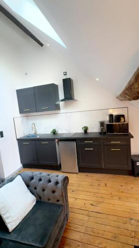 - une cuisine avec des armoires noires et un canapé dans la chambre dans l'établissement Le Loft, T2 duplex centre ville historique, à Bourges