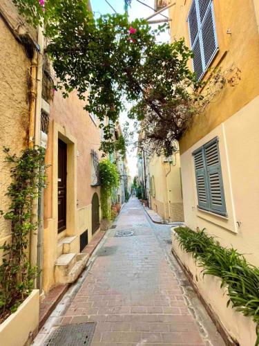une allée vide entre deux bâtiments fleuris dans l'établissement Spacieux studio - Vieil Antibes, à Antibes