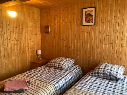 two beds in a room with wood paneled walls at Charmante maison au coeur d'un village auvergnat in Saint-Diéry