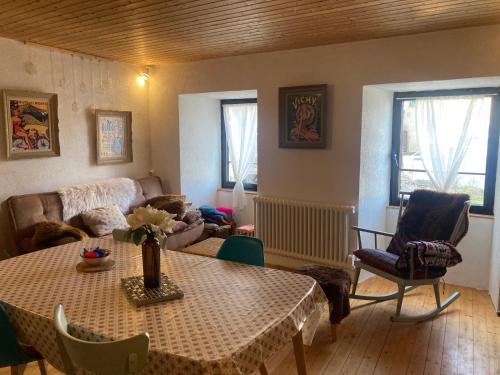 a living room with a table and a couch at Charmante maison au coeur d'un village auvergnat in Saint-Diéry