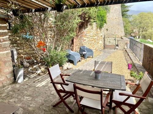 un patio avec une table et des chaises et un mur en pierre dans l'établissement La Maisonnette de Bédoin Mont Ventoux - Self Check In, à Bédoin