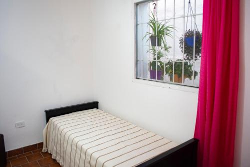 a bed in a room with a window and a red curtain at Tierra de Mariposas in Alta Gracia