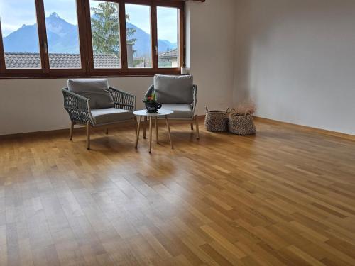two chairs and a table in an empty room with wood floors at Wohnung mit Herz in Schwyz