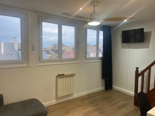 - un salon avec trois fenêtres et un ventilateur de plafond dans l'établissement Roch, à Fort-Mahon-Plage