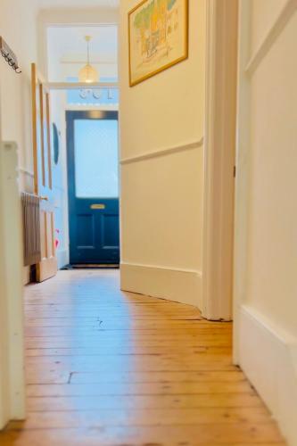 a hallway with a blue door and a wooden floor at Stylish Brighton Haven, Sleeps 1 to 7, free parking in Brighton & Hove