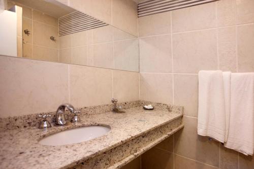 a bathroom with a sink and a mirror and towels at Hotel Plaza Apolo in Sao Paulo