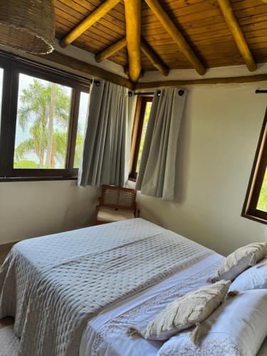 ein Schlafzimmer mit einem Bett und zwei Fenstern in der Unterkunft Suíte Deluxe com vista para Ilhabela in São Sebastião