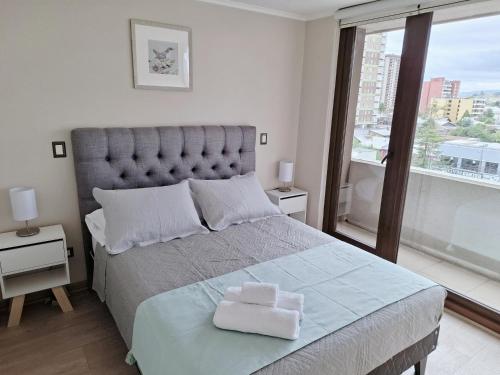 a bedroom with a large bed with two towels on it at Monstera, Depto 6 personas edificio Centro Lagos II in Temuco