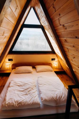 a bed in a small room with a window at Dobrede - будиночки під лісом in Dubrynychi