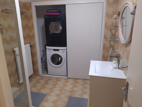 une salle de bain avec une machine à laver et un lave-linge dans l'établissement Grand T2 Hypercentre, rue calme, à Ax-les-Thermes