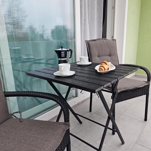 a black table and chairs with a cup of coffee and croissants at Apartman M&L 1 in Žgaljić