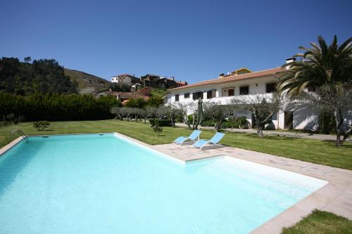 a swimming pool with two chairs and a house at Quinta Madureira in Alfolões