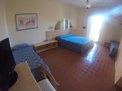 a small room with two beds and a mirror at Hotel Riviera in Alghero