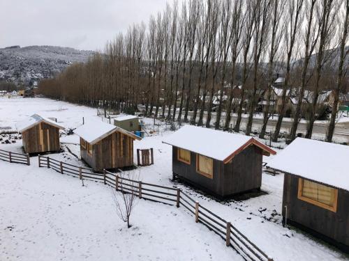 a group of huts in a snow covered field at TRAVELLERS Camping & Dorms in San Martín de los Andes