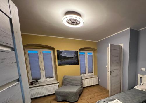 a bedroom with a bed and a chair and windows at Apartament MRĄGOWIA in Mrągowo