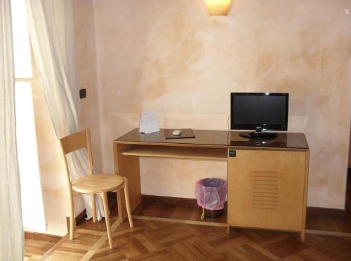Habitación con escritorio, TV y silla. en Hotel Clarean, en Nápoles