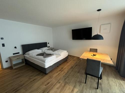 a bedroom with a bed and a table and a television at Apartments Vertain in Solda