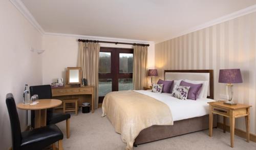 a bedroom with a bed and a desk and a chair at Delphi Resort Hotel & Spa in Leenaun