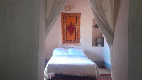 a bedroom with a bed and a picture on the wall at Dar Tamzdamte Skoura in Skoura