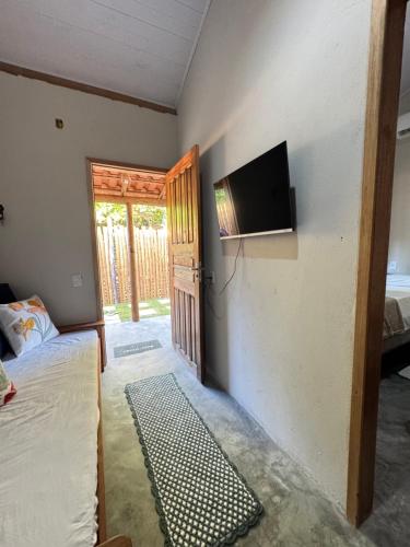 Una habitación con una cama y un televisor en una pared. en Vila Kairós, en Caraíva