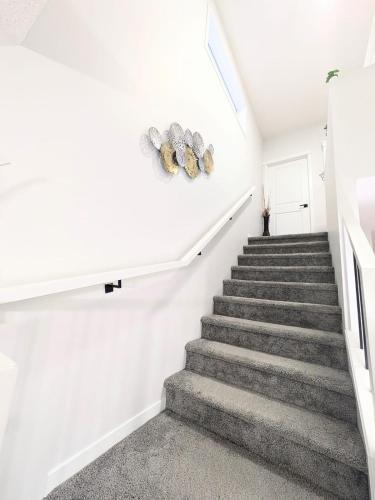 a staircase in a house with white walls and grey carpet at Edith Gate Luxe Bedroom 2 Homestay in Calgary