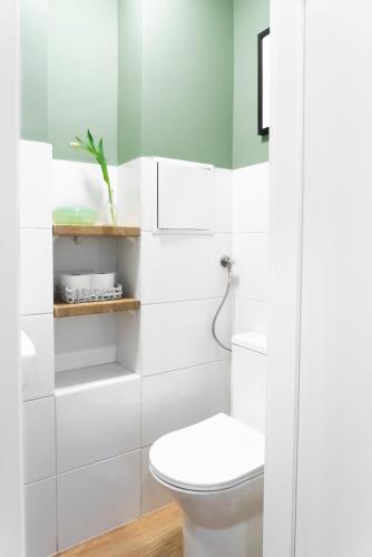 a bathroom with a white toilet and a green wall at Chmielna Central Apartments in Warsaw