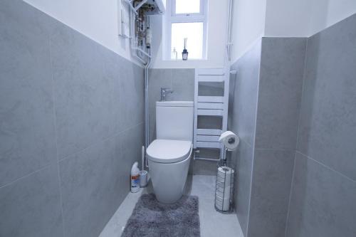 a small bathroom with a toilet and a window at Family House near Farnborough Airport, Free Parking in Hawley