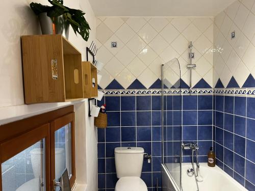 a blue tiled bathroom with a toilet and a tub at Maison Chez ACHILLE in Évreux