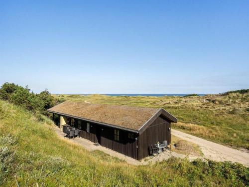 a building with a grass roof on a dirt road at 6 person holiday home in Pandrup-By Traum in Pandrup