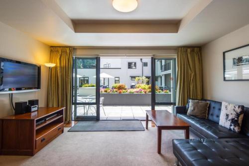 a living room with a couch and a tv at The Glebe Apartments in Queenstown
