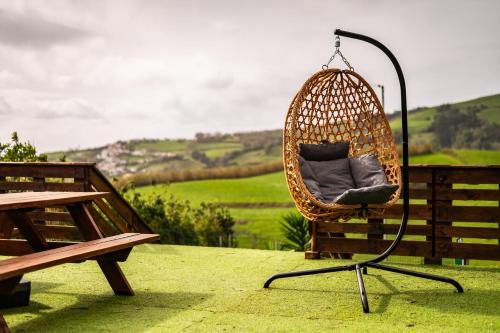 a wicker chair sitting next to a bench at Casa Xadrez in Povoação