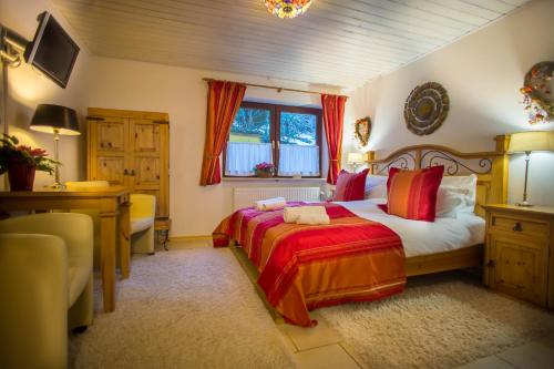 a bedroom with a bed and a desk and a window at Hotel Garni Zeranka in Ruhpolding