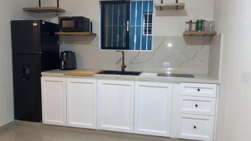 a kitchen with white cabinets and a black refrigerator at Solano Apartamentos in Boca Chica