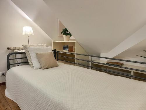 a bedroom with a white bed and a staircase at Casa das Escadinhas in Ericeira