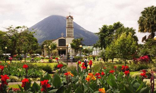 a church with a mountain in the background with flowers at Cabaña ITZE in Fortuna