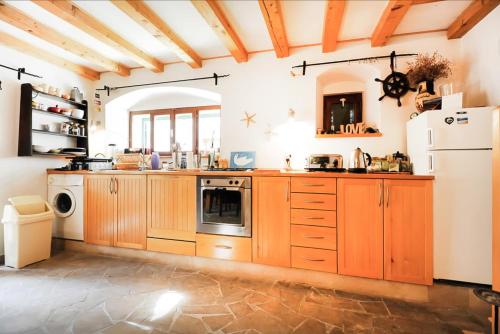 a kitchen with wooden cabinets and a white refrigerator at Torriano Holiday House in Šibenik