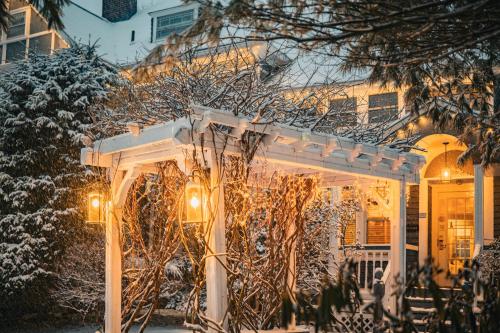 a white pergola in front of a house in the snow at The Cornell Inn, Lenox & The Berkshires in Lenox