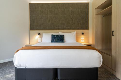 a bedroom with a large white bed with a blue pillow at Copthorne Hotel & Resort Bay Of Islands in Paihia