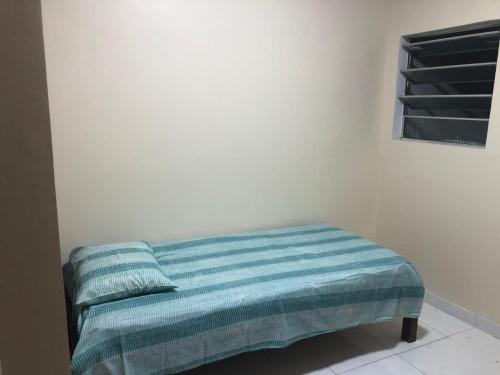 a bed in a room with a blue blanket at Apto de tuco in Ilhéus