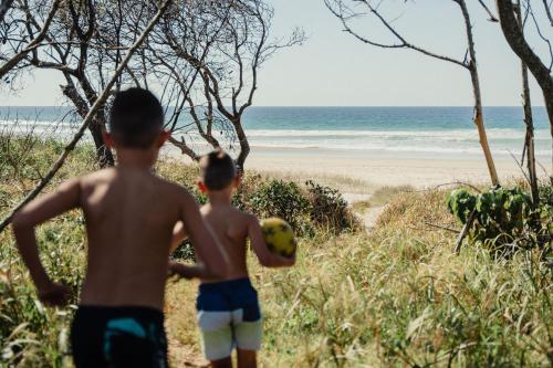 two young boys playing with a soccer ball on the beach at Tweed Holiday Parks Pottsville North in Pottsville