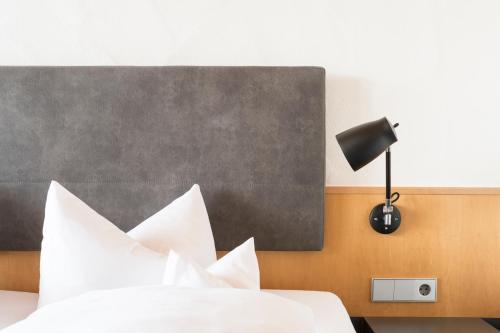 a bedroom with a bed with white pillows and a lamp at Appartement Hotel Seerose in Immenstaad am Bodensee
