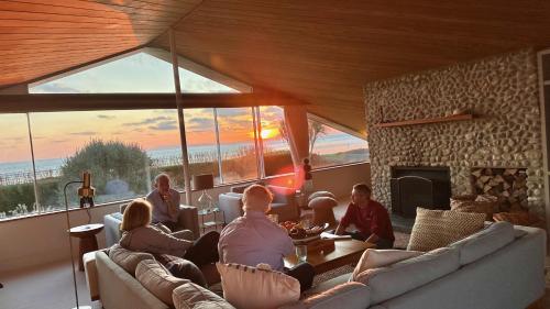 a group of people sitting in a living room with a fireplace at Vegan Seafront Retreat & Yoga Studio in West Wittering in West Wittering