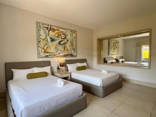 ein Schlafzimmer mit zwei Betten und einem Gemälde an der Wand in der Unterkunft Awesome apartment at Aldea Thai Beachfront in Playa del Carmen